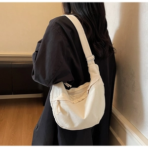 Détail de profil d'un sac demi-lune en toile blanc cassé avec bandoulière ajustable