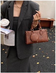Detail of a vintage brown leather handbag with round handles and a matching coin purse charm