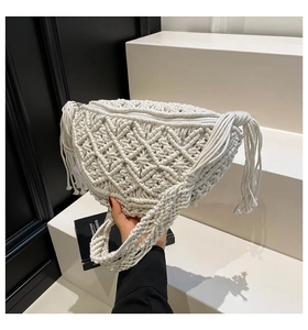 Detail of white bohemian woven crossbody bag with diamond pattern and side fringe tassels