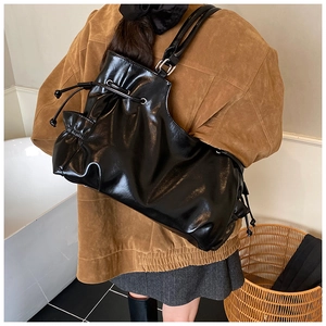 Detail of black glossy tote bag with stylish drawstring pleated sides for daily commute