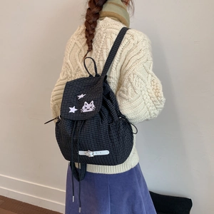 Detail of black plaid drawstring backpack with cute cat embroidery on a female model