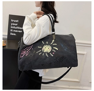 Black canvas travel tote with colorful graffiti prints and leather handles shown on shoulder