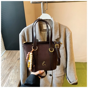 Dettaglio borsa a secchiello in pelle scamosciata marrone con logo L e perline in legno