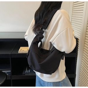 Détail du grand sac croissant en toile noire avec boucle argentée et large bandoulière