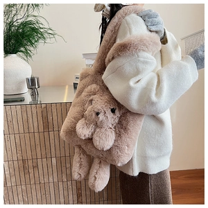 Detail of plush tote bag with 3D teddy bear charm on model in soft home setting