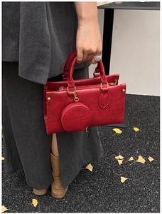 Detail of red vintage leather handbag with matching round coin purse on autumn leaf background