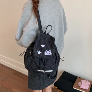 Detail view of black plaid backpack featuring cute purple cat embroidery and drawstring pockets