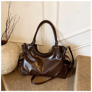 Detail of a dark brown leather tote with side drawstring and versatile shoulder straps