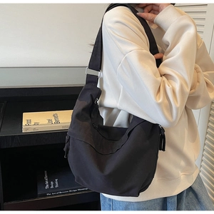 Détail d'un sac bandoulière en toile noire avec sangle réglable et boucle en métal argenté