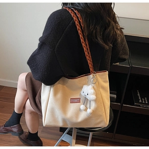 Detail of off-white canvas tote bag with brown woven strap and cloud charm pendant