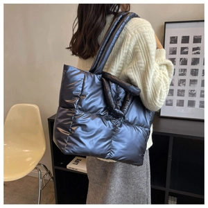 Detail view of navy blue metallic puffer tote bag featuring quilted texture and thick handles