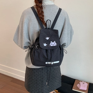 Close-up of black plaid canvas backpack featuring star and purple cat embroidery details