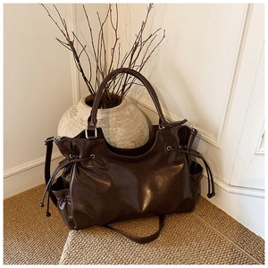 Detailed shot of dark brown tote bag showing glossy faux leather texture and side drawstrings