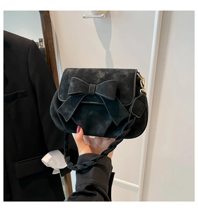 Dettaglio della borsa a sella nera opaca con fiocco grande e tracolla intrecciata e ganci oro