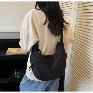 Détail du sac bandoulière croissant noir en toile avec nœuds décoratifs sur le côté