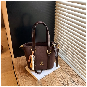 Dettaglio di una borsa tote in pelle scamosciata marrone con logo L dorato e ciondoli
