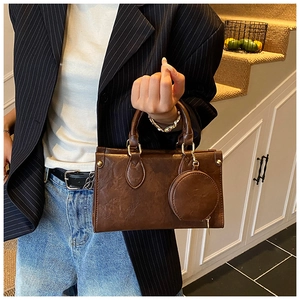 Detail of vintage brown textured leather handbag with a matching round mini coin purse charm