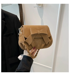 Dettaglio della borsa a sella opaca color cammello con fiocco 3D e manico intrecciato
