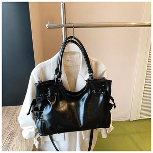 Detail of black faux leather tote bag with side drawstrings and double handles