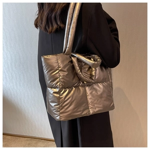Metallic quilted tote bag with thick padded handles shown in a lifestyle street view