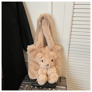 Close-up of fluffy plush bear tote bag detail on a silver luggage case in home setting