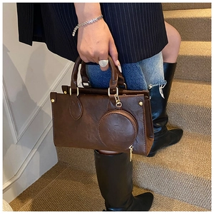 Detail of dark brown matte faux leather tote bag with round coin purse and gold hardware