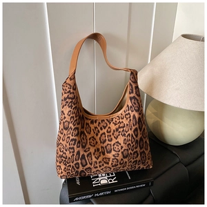 Detailed view of the leopard print hobo bag with leather strap on a decorative book