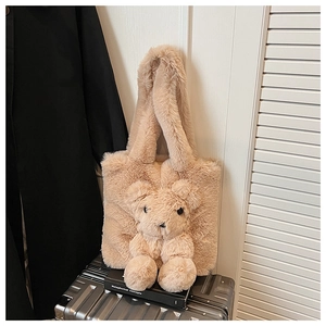 Detail of plush teddy bear tote bag in beige faux fur on a silver suitcase