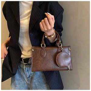 Detail of retro brown pleated leather tote bag with gold hardware and mini round pouch