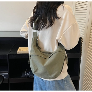 Détail du sac croissant en toile vert foncé montrant le tissu et la bandoulière