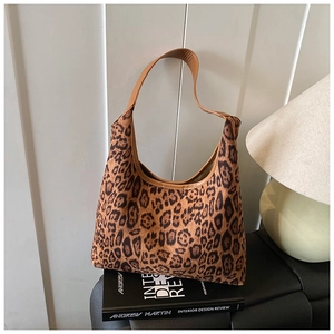 Detail of vintage leopard print hobo bag with brown leather strap on a design book