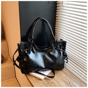 Detailed view of the shiny black leather tote bag with drawstrings and dual straps