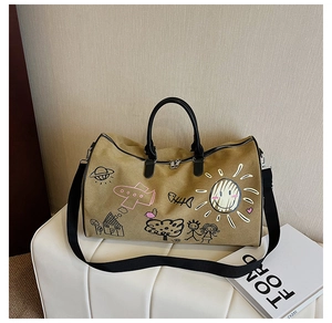 Detail of canvas travel bag with cartoon graffiti patterns and black leather handles