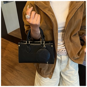 Detail of black mini square handbag with round coin purse charm and gold hardware