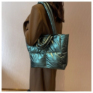 Model showing metallic green quilted down tote bag with a padded shoulder strap style