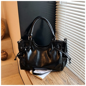 Close-up of black polished faux leather tote bag showing side drawstring detail