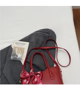 Dettaglio della borsa a secchiello in pelle bordeaux con foulard di seta festivo