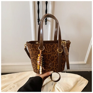Dettaglio borsa a secchiello scamosciata leopardata con ciondolo e logo metallico
