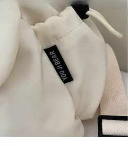 Detail of the woven brand tag and adjustable strap on a minimalist canvas backpack