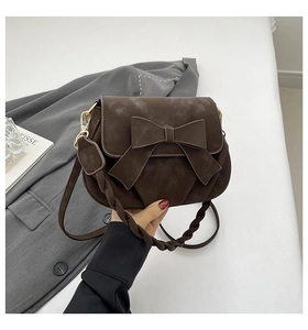 Dettaglio borsa a sella marrone opaca con grande fiocco e tracolla intrecciata moda