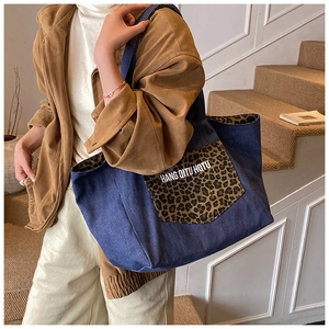 Detail of blue denim tote bag with leopard print pocket and stylish white lettering