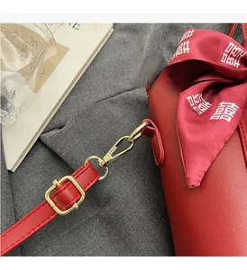 Dettaglio della borsa tote rossa con fibbie in metallo dorato e sciarpa di seta decorativa