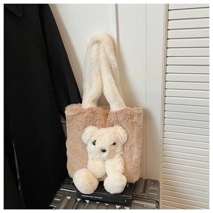 Close-up of fluffy plush tote bag with cute stuffed bear on silver suitcase