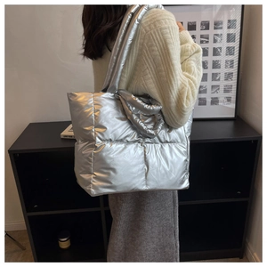 Detail of silver metallic quilted tote bag with wide shoulder straps on a female model