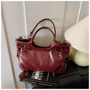 Deep red glossy leather tote bag with drawstring details and silver hardware accessories