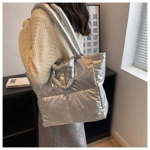 Detail of silver metallic quilted tote bag with padded shoulder straps shown on a model