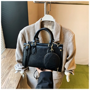 Detail of black pebbled leather handbag with detachable round coin purse and gold hardware