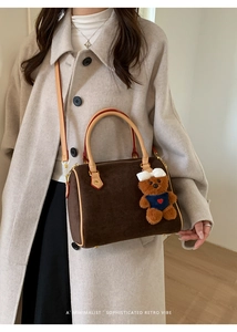 Close-up of retro brown suede boston bag with leather handles and cute bear charm