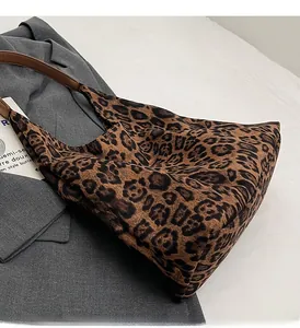 Detail of leopard print tote bag with brown faux leather handles on a grey blazer