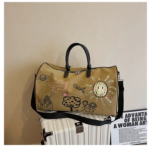 Detailed view of khaki canvas travel bag featuring artistic graffiti prints and black handles